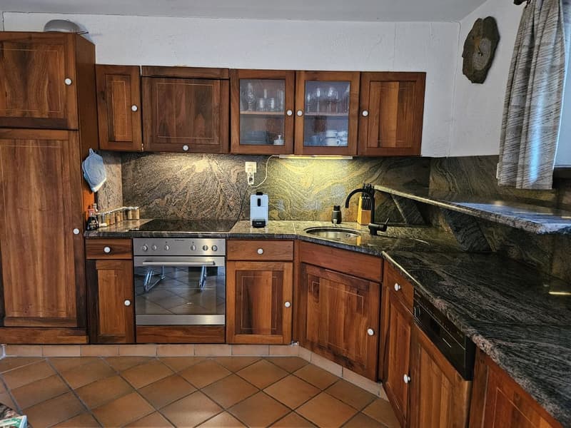 Wooden cabinets, granite countertops, stainless steel appliances including a stove and dishwasher, tiled floor