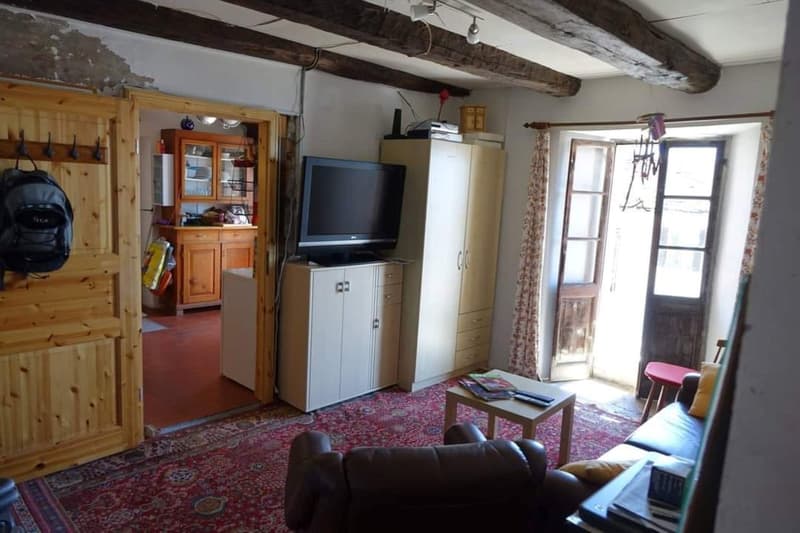 rug, large windows, TV, wooden cabinet, armchair, table, backpack, couch