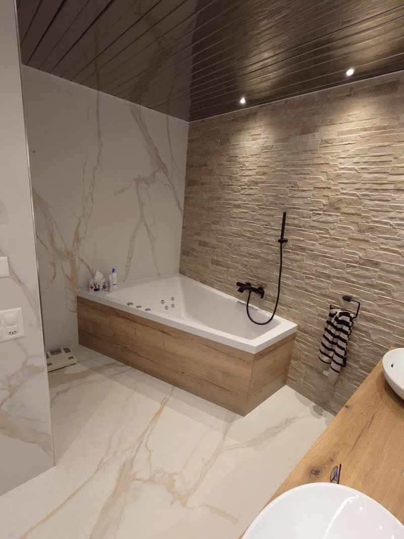 marble wall, large bathtub, wooden shelf, white sink
