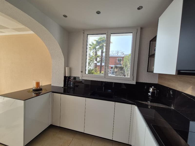modern kitchen with white cabinets, black granite countertops, open window overlooking a garden, natural light, stainless steel faucet