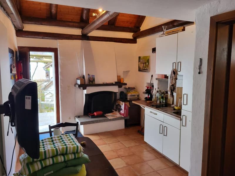 fireplace, white kitchen cabinets, tiled floor, black stove, refrigerator, sink