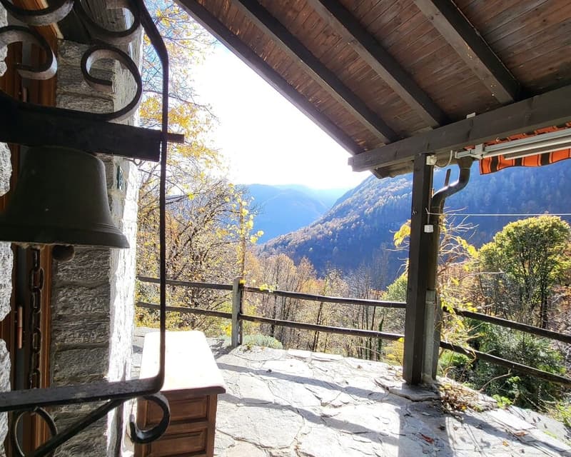 wooden ceiling, stone wall, wooden desk, wooden railing, bell, view of mountains