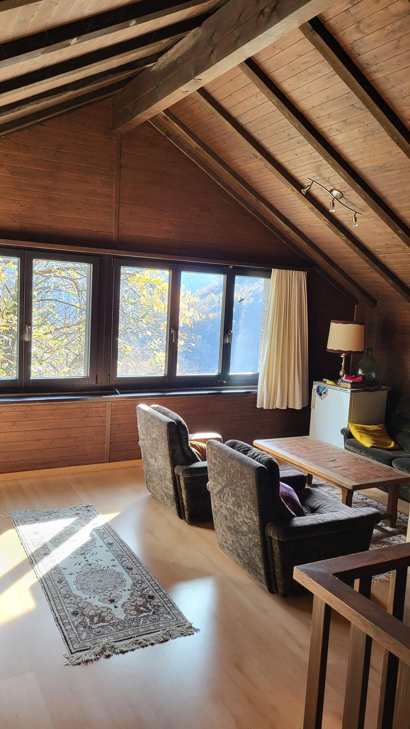 wooden ceiling, wooden floor, large windows, two armchairs, coffee table, rug, lamp, refrigerator