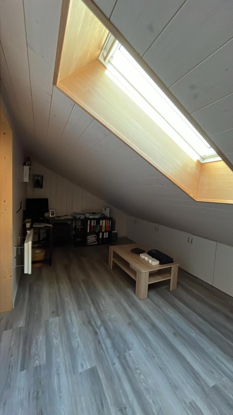 attic room with desk, coffee table, shelves, radiator, skylight