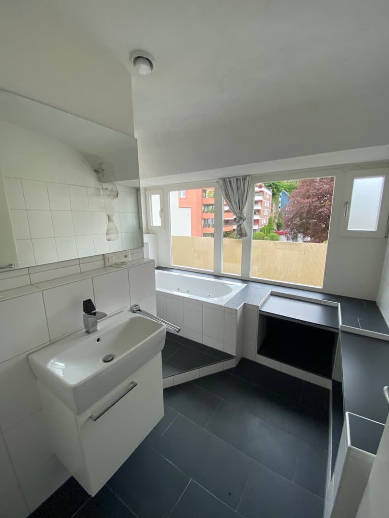 modern bathroom with bathtub, sink, mirror, and large window