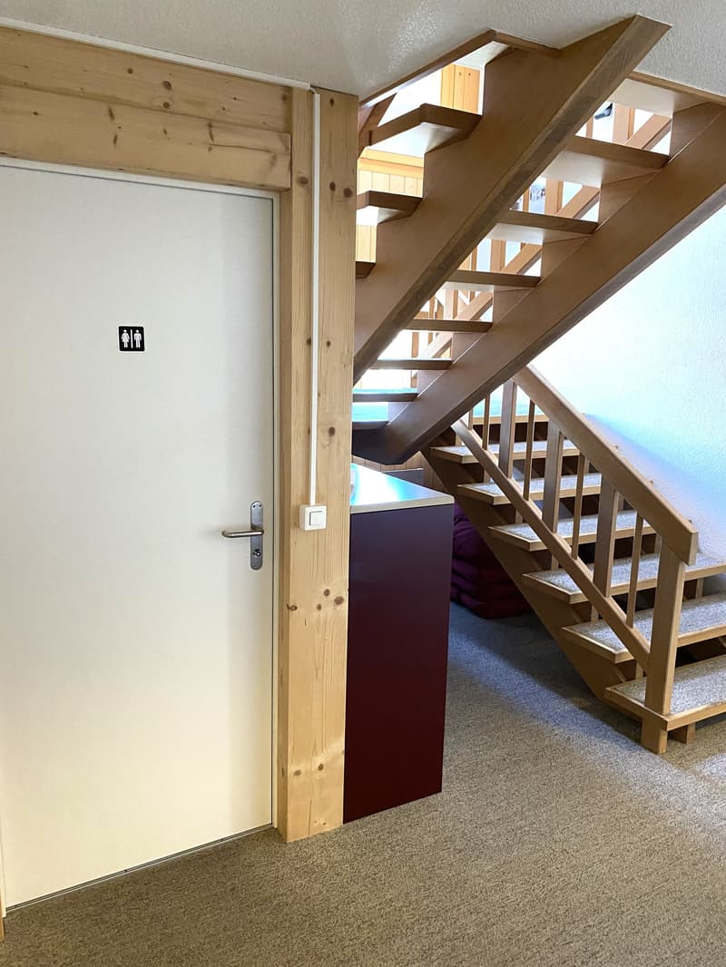 white door, wooden stairs, carpeted floor, wooden pillar, small cabinet