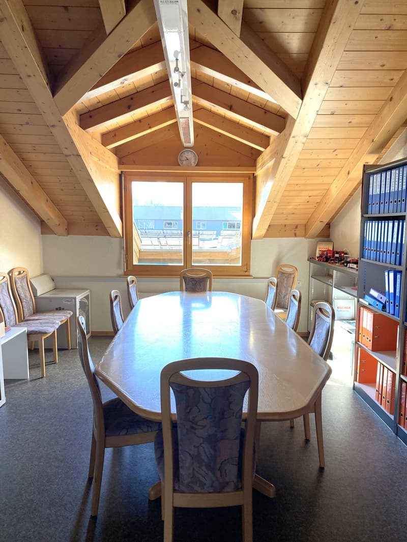 meeting room with wooden ceiling, large table, chairs, window, clock, shelves with books