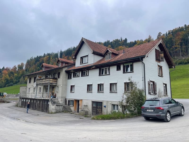 House with multiple floors, concrete walls, brown roof, stairs, parked car, grassy lawn