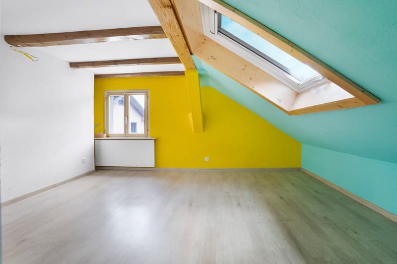 Attic room with exposed wooden beams, yellow and turquoise walls, hardwood flooring, and a skylight window
