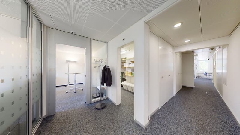 Corridor with entrance, open office space, storage area with shelves, hallway with tables, open hallway.