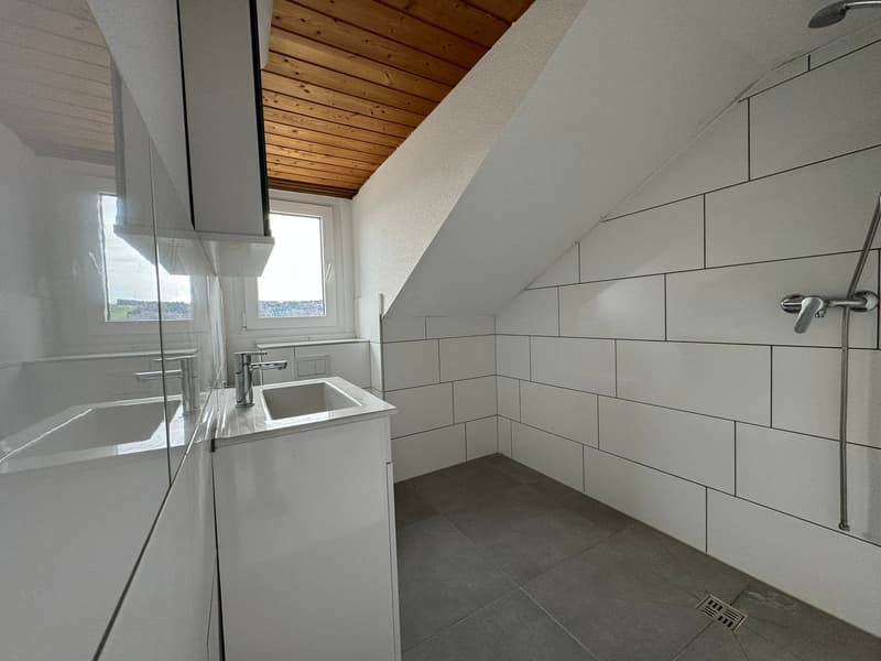 a small bathroom with a wooden ceiling, white tiled walls, white shower stall, sink with mirror, and a window