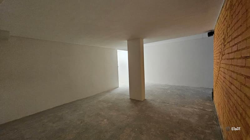 An empty room with a pillar, white walls and a grey concrete floor