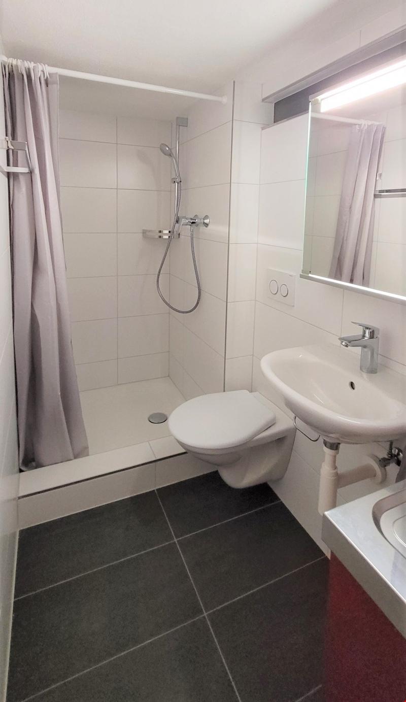 Bathroom with shower, toilet, sink, mirror, and tiled floor
