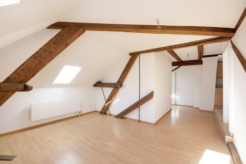empty room, wooden beams, wooden floor, white walls, radiator, skylight
