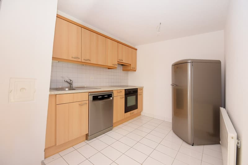 modern kitchen with wooden cabinets, stainless steel appliances, white tiled floor, and white walls