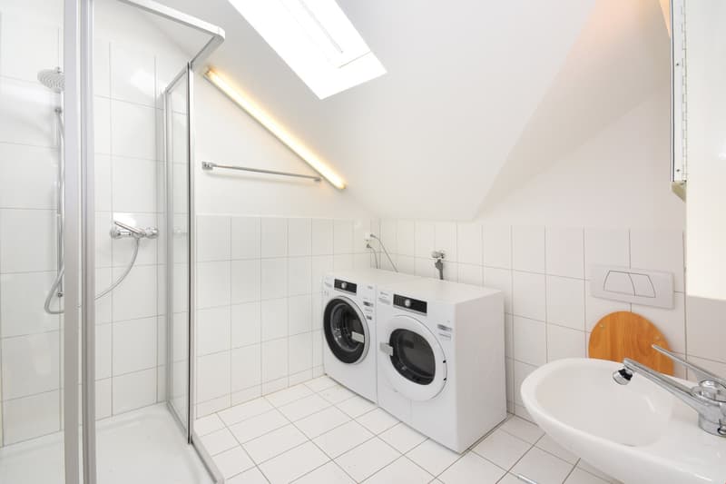 white tiled walls, glass shower, washing machine, sink, wooden toilet seat