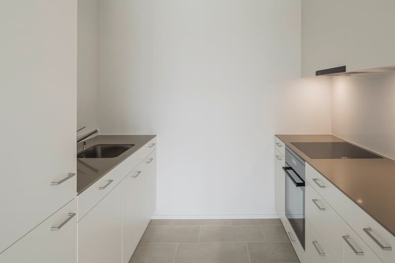 modern kitchen with white cabinets, stainless steel sink, induction cooktop, built-in oven, and tiled floor