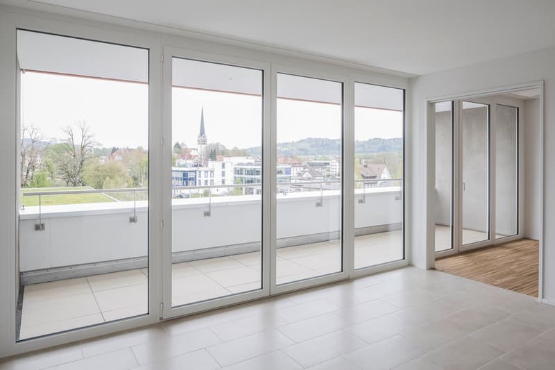 large sliding glass doors, balcony, tiled floor, white walls, view of the city
