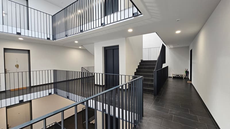 modern staircase with black railings, black tiled floor, white walls, multiple levels with balconies