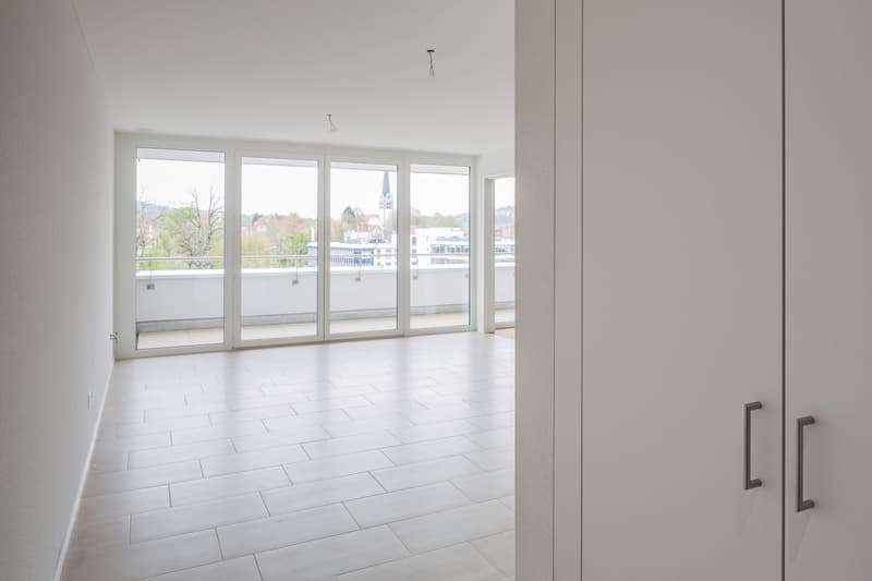 empty room, white tiles, large sliding glass doors, balcony, city view