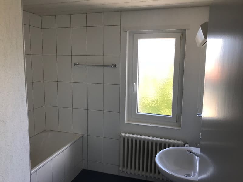 Tiled walls, window, radiator, sink, and a washing machine
