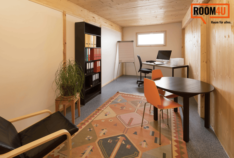 Spacious office with wooden walls and ceiling, large window, desk with computer, office chair, bookshelf, plant, and patterned area rug