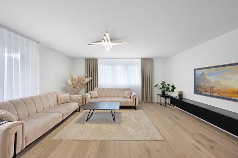 modern living room with beige sofas, wooden floor, beige rug, coffee table, side table, curtains, painting, plant