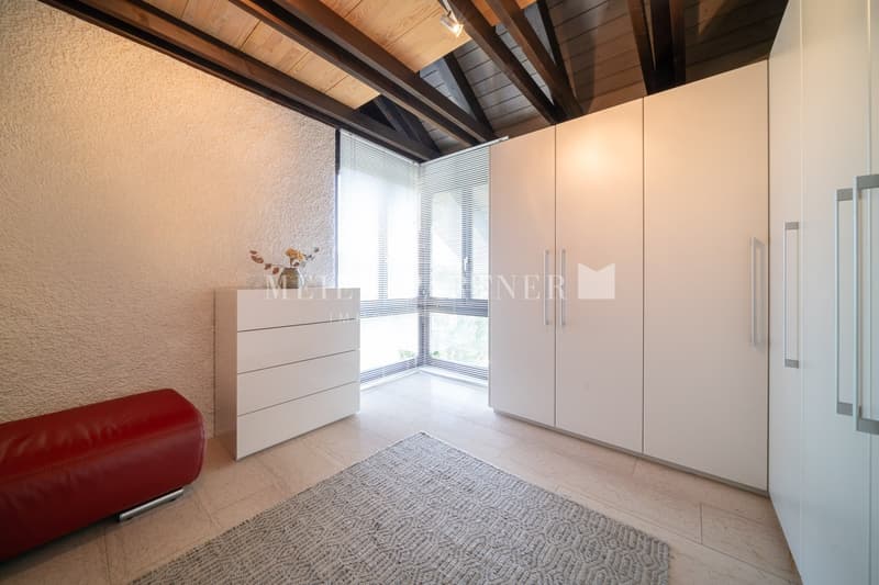 tiled floor, white cabinet, red couch, rug, windows with blinds, exposed wooden beams on ceiling