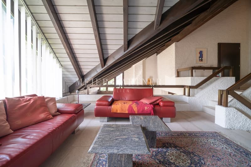 red leather couches, two tables, carpet, metal stairs, white ceiling