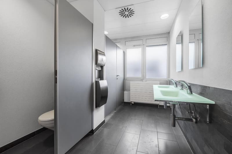 modern bathroom with white tiles, sink, mirrors, toilet, tissue dispenser, air extractor