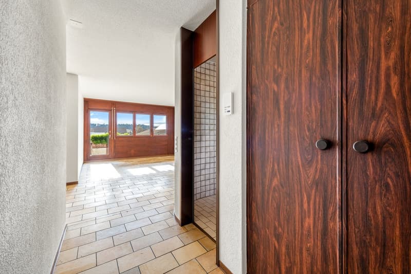 white wall, tile floor, wooden door, light coming from glass door