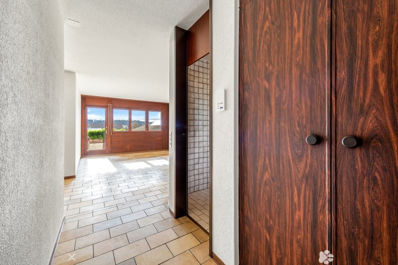 white wall, tile floor, wooden door, light coming from glass door