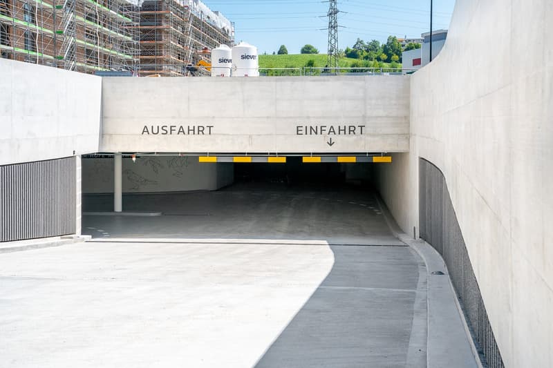 modern design, concrete construction, signs indicating entry and exit, empty car park