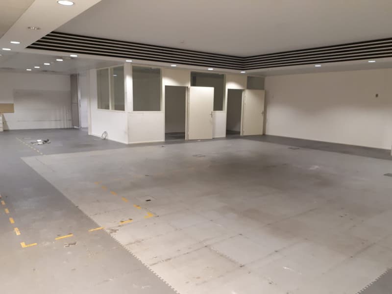 an empty warehouse or commercial space, white walls, high ceiling, doors, glass windows, raised ground floor