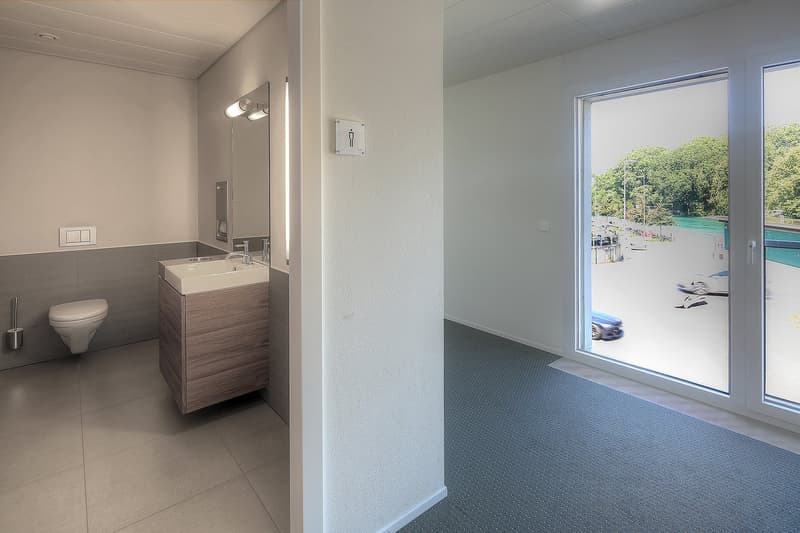 Modern bathroom with vanity sink, toilet, and large window overlooking outdoor scenery