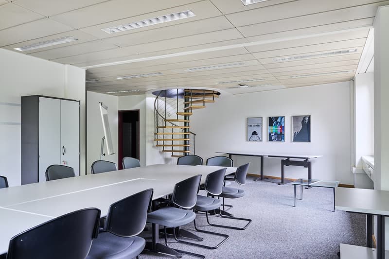 long rectangular table, chairs, spiral staircase, whiteboard, artwork on walls