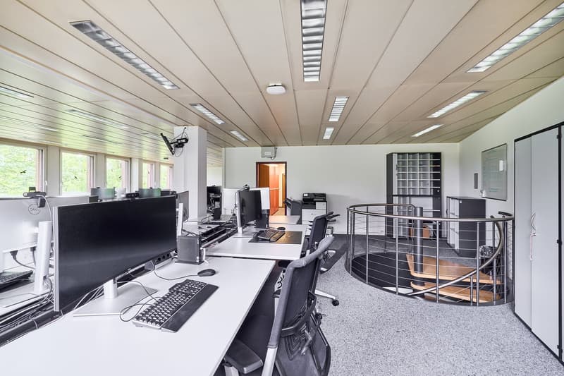 modern office setup, multiple computers, keyboard, mouse, monitor, desks, chairs, central staircase