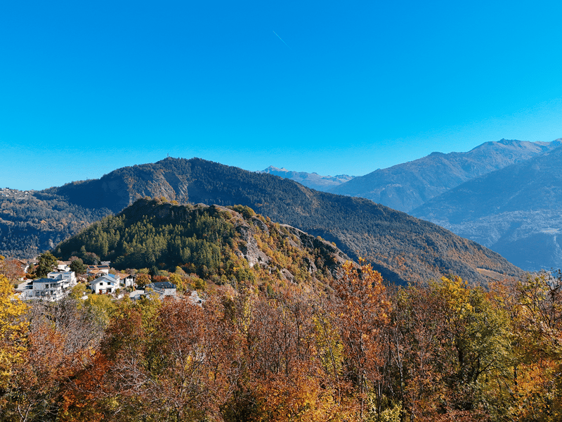 Mountain landscape with trees, houses, and a clear blue sky