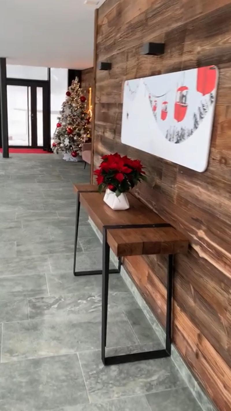 Rustic wooden wall paneling, Christmas tree, red poinsettia flowers, wooden console table, framed artwork on the wall