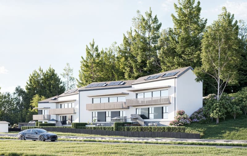 Modern multi-story apartment building with white exterior, large windows, balconies, and solar panels on the roof. The building is surrounded by lush greenery and a car is parked in the foreground.