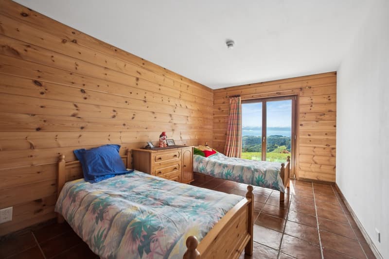 Bedroom with two wooden beds, nightstand, wooden walls, tiled floor, glass sliding door with view.