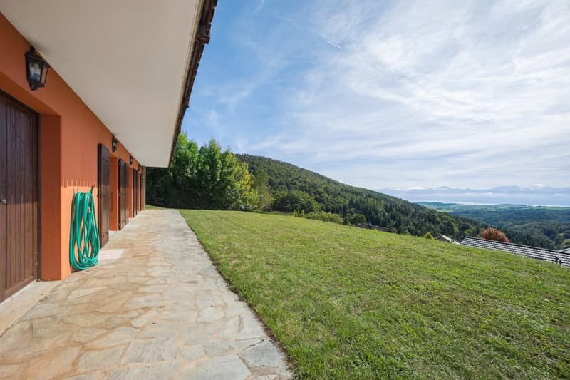 orange walls, stone path, green hose, grass, mountains, blue sky