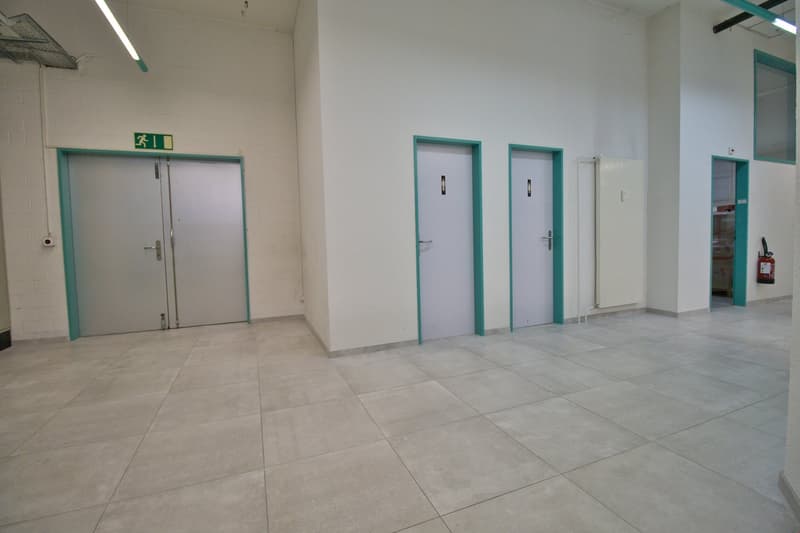 Empty room with white walls, tiled floor, three doors, and a fire extinguisher