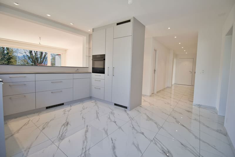 modern kitchen with white marble flooring, white cabinets, built-in oven, large window