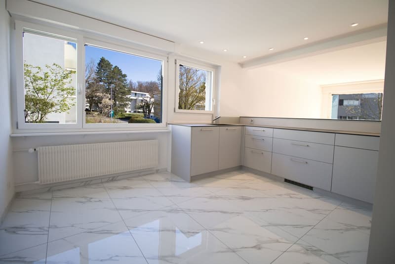 modern kitchen with white cabinets, marble flooring, large windows, radiator