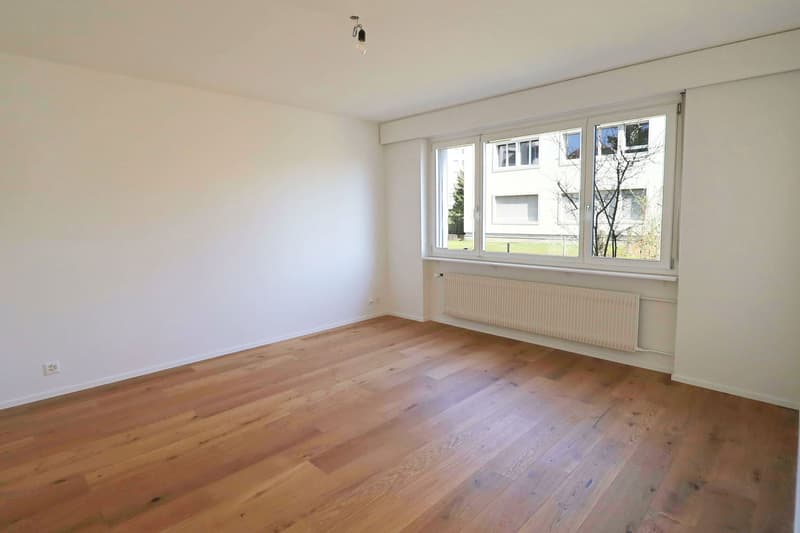empty room, wooden floor, white walls, large window, white radiator
