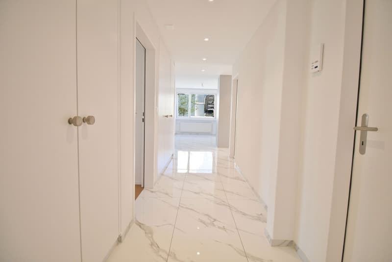 white marble floor, white walls, doors on both sides, hallway leading to rooms