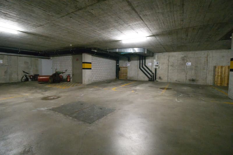 Empty parking lot with concrete floor, yellow markings, and a fire extinguisher.