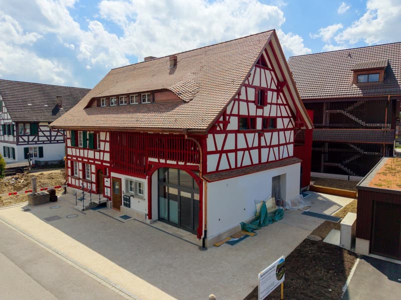 2 story house, red and white exterior, brown roof, large windows, balcony, garage
