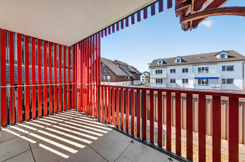 Balcony with red railings, tiled floor, view of the outside